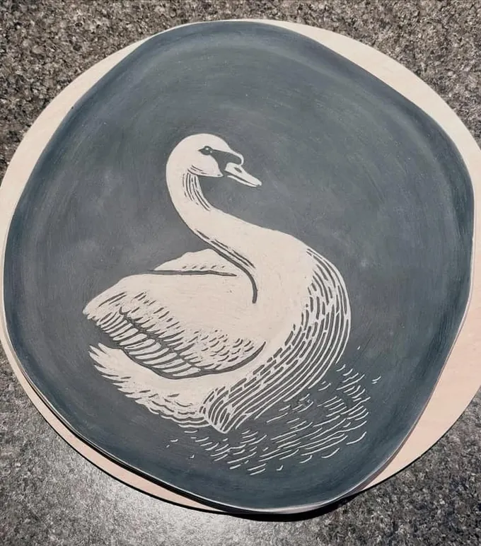 Swan plate carved through grey slip
